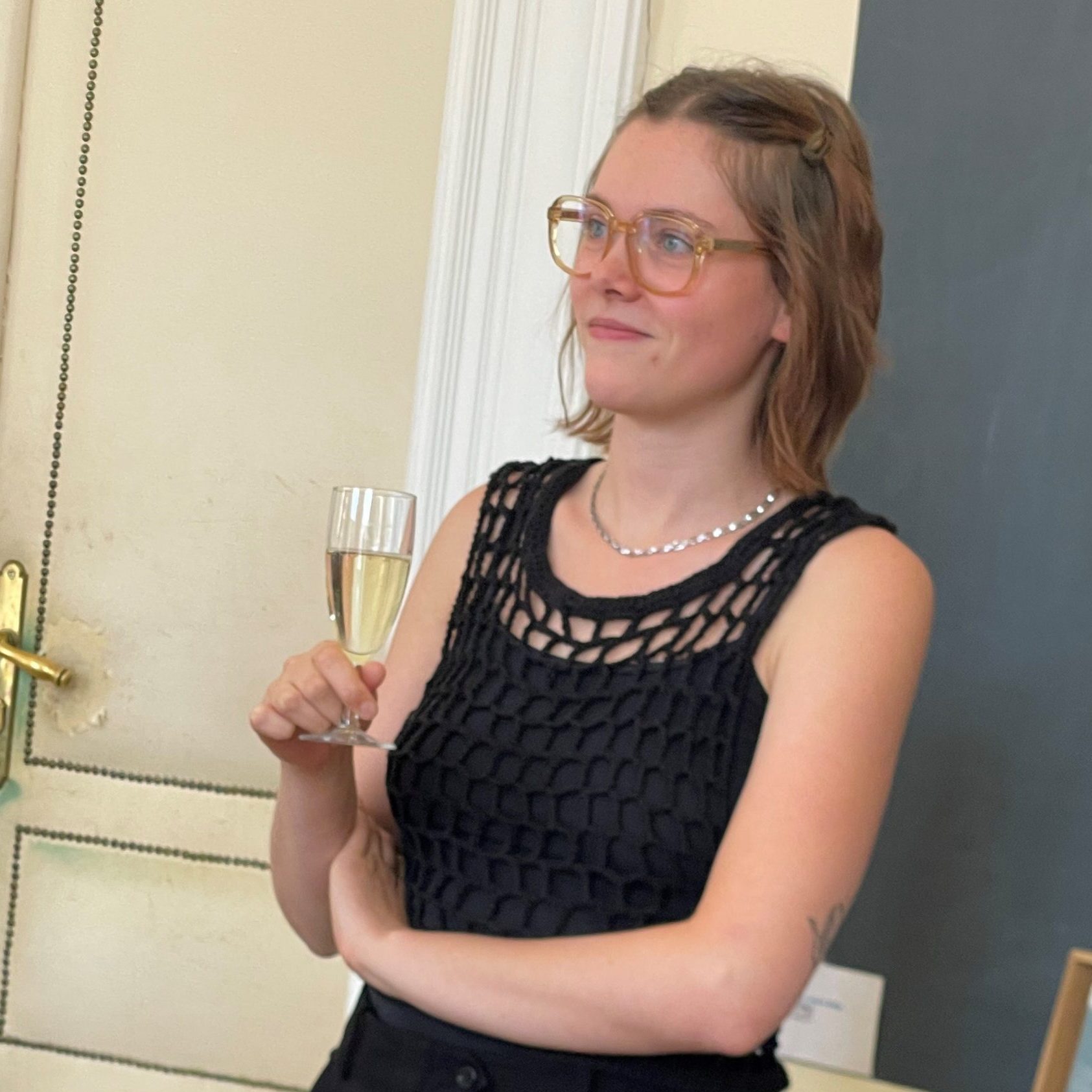 Portraitfoto von Kathi Waltl mit Sektglas in der Hand. Sie lächelt, schaut aber nicht in die Kamera.